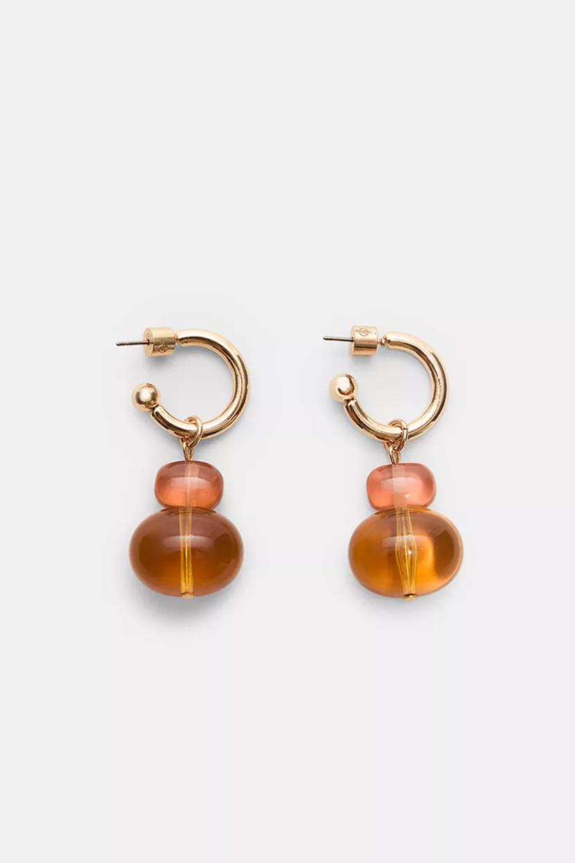 Gold hoop earrings with amber drops on a white background